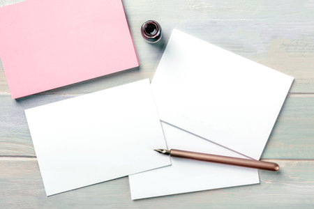 Stationery mock-up with an ink bottle and a nib pen. Blank greeting cards or invitations, shot from...