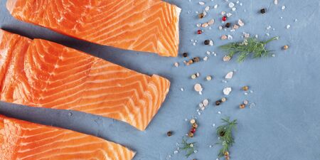 Raw salmon with salt, pepper, and dill, overhead panorama with a place for text. Cooking fish, a flatlayの写真素材