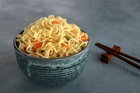 Instant noodles bowl with carrot and scallions, with chopsticksの写真素材