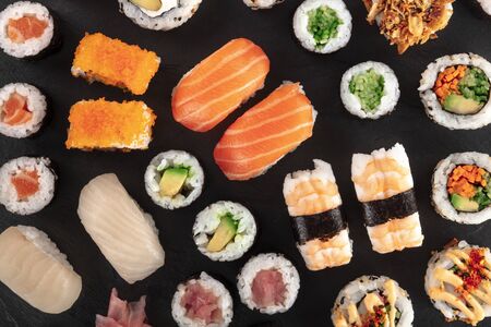 Large sushi set, shot from the top on a black background. A flat lay of various maki, nigiri and rollsの写真素材