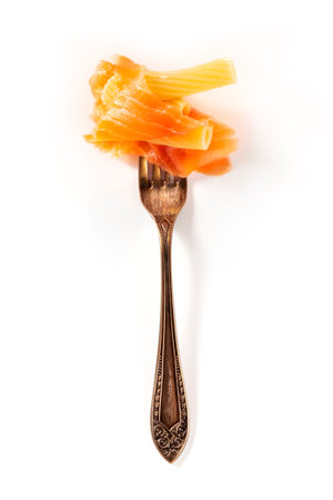 Italian pasta. A vintage fork with penne and smoked salmon, on a white background with copy space