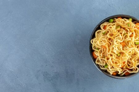 Instant noodles with carrot, scallions, and a sauce, a vegetable soba bowl, close-up shot from above with a place for textの写真素材