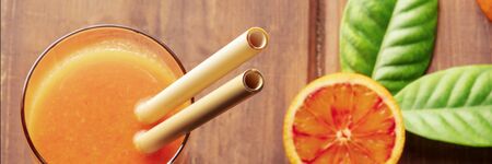 Reusable bamboo straw panorama on a rustic wooden background, fresh orange juice with blood oranges, shot from above, selective focusの写真素材