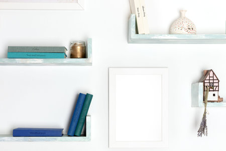 Poster mockup. A blank frame for a drawing on a wall with books and objects