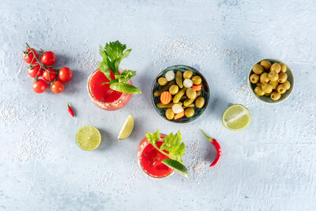 Bloody Mary cocktails, shot from the top. Tomato juice mix with celery and lime, with olives and...