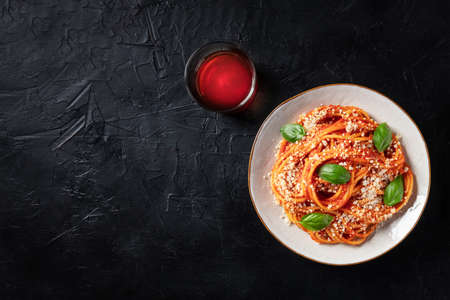 Spaghetti pasta with tomato sauce, Parmesan cheese and fresh basil leaves, shot from the top on a black backgroundの写真素材