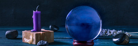 Fortune telling panorama. A magic ball with a candle, crystals and herbs