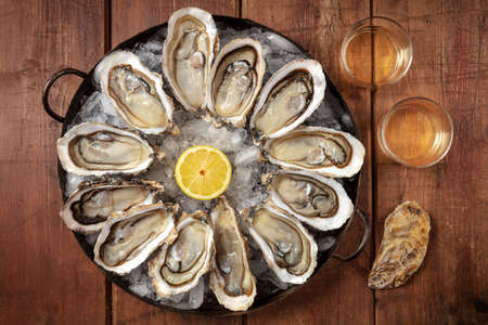 Oysters and wine. A dozen of fresh oysters with lemonの写真素材