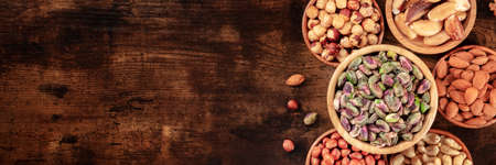Nut panorama, overhead flat lay shot with copy space on a dark rustic wooden backgroundの写真素材