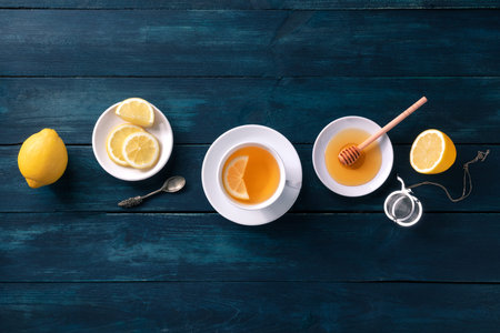 Lemon tea with honey, shot from the top on a dark rustic wooden background. Healthy organic citrus...