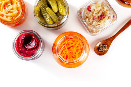Fermented food on a white background with a place for text. Canned sauerkraut, carrot, pickles and other preserves in glass jars. Homemade vegan cooking. Probiotic foodsの写真素材