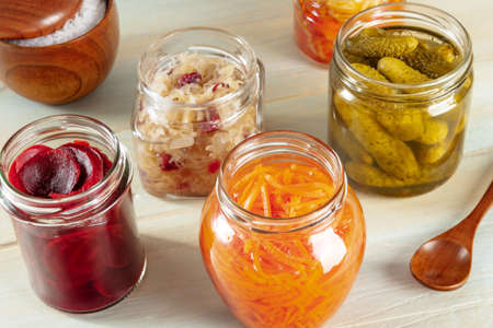 Probiotic foods. Fermented food. Canned sour cabbage, carrot, pickles and other preserves in glass jars. Homemade vegan cooking on a rustic wooden backgroundの写真素材