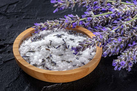 Lavender sea salt with a bunch of lavandula flowers, aromatic herb for cooking or a bath salt for spa, on a black backgroundの写真素材