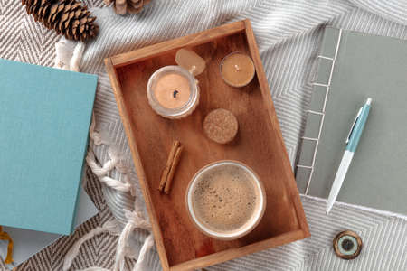 Hygge. Cozy winter morning. A cup of coffee with scented candles, a journal, a warm blanket, and some books, overhead flat lay shotの写真素材