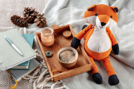Hygge still life with a toy fox, a cup of coffee, and scented candles. Cozy weekend morning, staying at home in cold weatherの写真素材