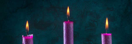 Candle panorama with burning purple candles on a dark blue backgroundの写真素材