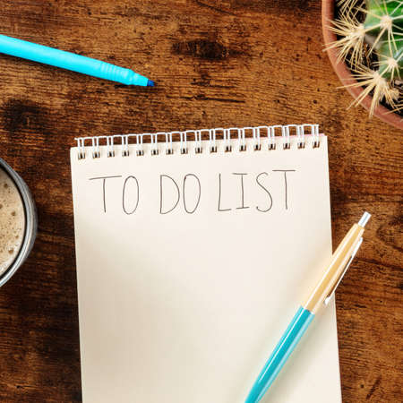To do list. Overhead square shot of a turquoise blue pen and a notebook on a wooden desk. The concept of planning, time managementの写真素材