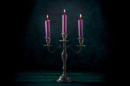 Burning candles in a vintage candle holder on a dark backgroundの写真素材