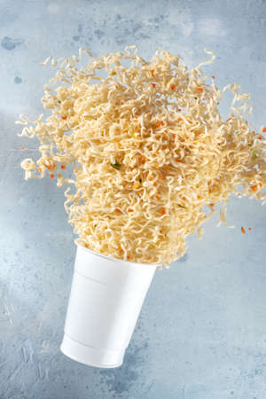 Ramen cup with instant noodles flying out of it, fast food levitationの写真素材