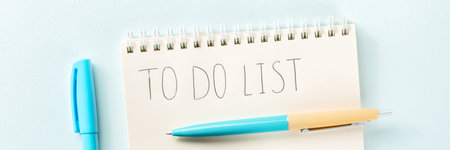 To do list panorama. A paper notebook with a pen, shot from above on a blue background. The concept...