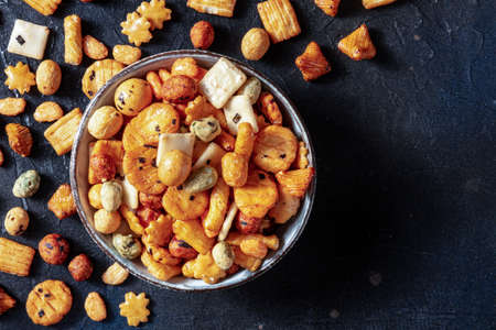 Japanese rice crackers in a bowl on a black slate background, overhead flat lay shot with copy spaceの写真素材