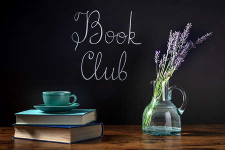 Book Club Concept. A stack of books and a cup of coffee on a desk with chalk lettering and lavender flowersの写真素材