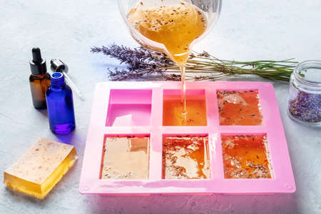 Organic handmade soapmaking. Diy cosmetic, the process of making. Liquid glycerin with essential oils and lavender buds is poured into a silicone soap moldの写真素材