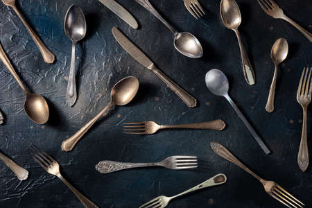 Cutlery pattern. Various forks, knives, and spoons, elegant tableware, overhead flat lay shot on a black backgroundの写真素材