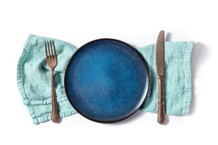 Cutlery with a blue plate. A fork, a knife, and a dish on a teal napkin, overhead flat lay shot on a white backgroundの写真素材