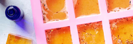 Handmade soap making. Diy glycerin based soap drying in a mold, shot from the top with essential oils, panoramaの写真素材