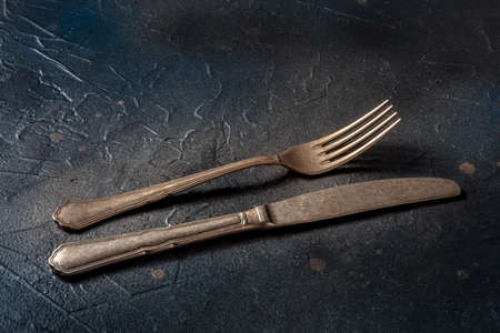 Cutlery. A knife and fork on a black slate background. Modern silverware on a dark tableの写真素材