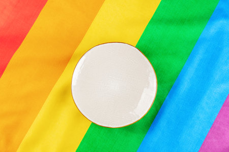 Gay food concept. A plate, shot from above on the LGBTQ rainbow flag texture, a restaurant menu designの写真素材
