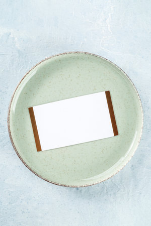 Dinner invitation. A card on a green plate, top shot on a slate background. Place settingの写真素材