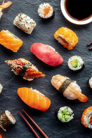 Sushi, shot from the top with chopsticks and soy sauce. Rolls, maki, nigiri on a black background, Japanese food. Salmon, tuna, eel, shrimp and other seafoodの写真素材