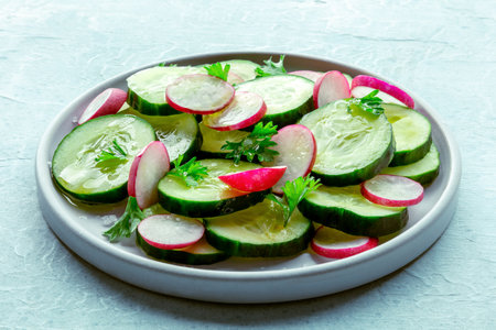 Fresh cucumber and radish salad with parsley. Simple vegan recipe on a slate background. Healthy dietの写真素材