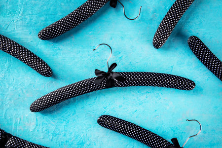 Fashion collection concept. Black satin hangers for delicate clothes, a flat lay layout on blue....