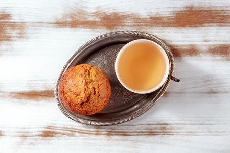 Orange muffin with tea on a rustic wooden kitchen table, on a vintage tray, overhead flat lay shotの写真素材