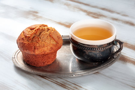 Orange muffin with tea on a rustic wooden kitchen table, on a vintage trayの写真素材