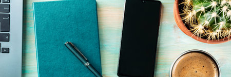 Desk, top view panorama. Coffee, notebook, phone, plant, and laptop, shot from above on a blue...