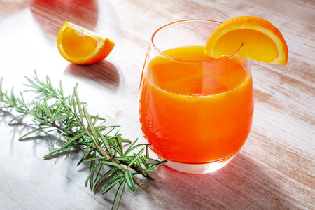 Fresh orange drink with rosemary on a wooden background, a cocktail or a mocktailの写真素材