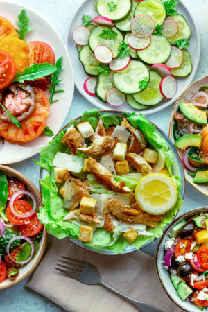 Fresh salads, overhead flat lay shot of an assortment. Variety of plates and bowls with green vegetables. Caesar salad with chicken and othersの写真素材
