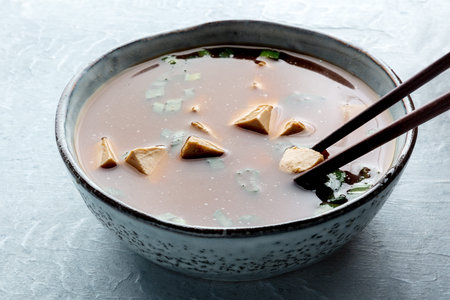 Eating tofu soup, Japanese cuisine. Miso soup with bean curd and green onions, a close-up with...