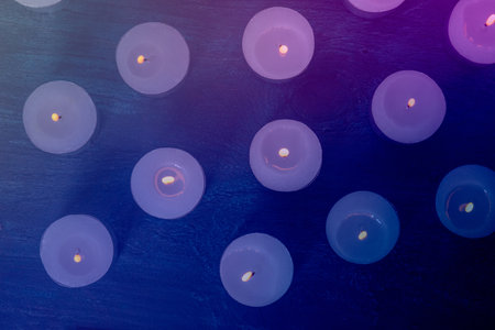 Tea light candles on a dark background, many lights in the dark, candlelight, toned imageの写真素材