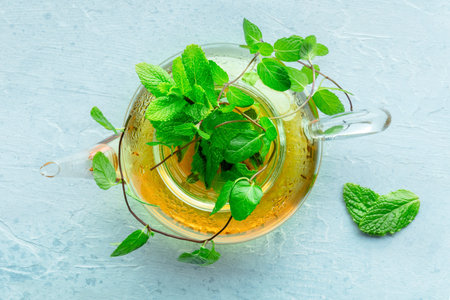 Mint tea. A tea pot with fresh mint leaves steeping in hot water, shot from the top on a blue...
