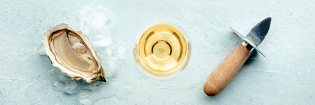 Fresh raw oyster with a glass of white wine and an oyster knife, on ice, on a slate background,...