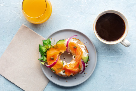 Lox bagel. A breakfast of a sandwich with smoked salmon and fresh vegetables on a plate, with orange juice and coffee, overhead flat lay shotの写真素材