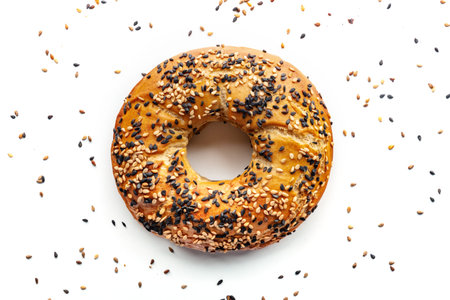 Bagel with sesame seeds, overhead flat lay shot on a white background, freshly baked