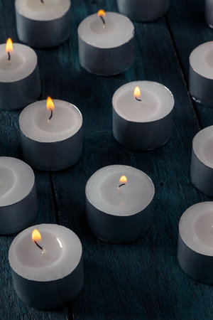 Tea light candles on a dark background, many lights in the dark, candlelightの写真素材