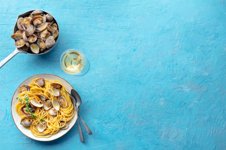 Vongole clams with spaghetti pasta, with white wine, overhead flat lay shot. Seafood linguine on a blue background with copy spaceの写真素材