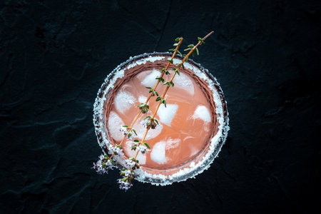 Salty Dog cocktail with fresh grapefruit juice, lime juice, and thyme, overhead flat lay shot on a black slate backgroundの写真素材